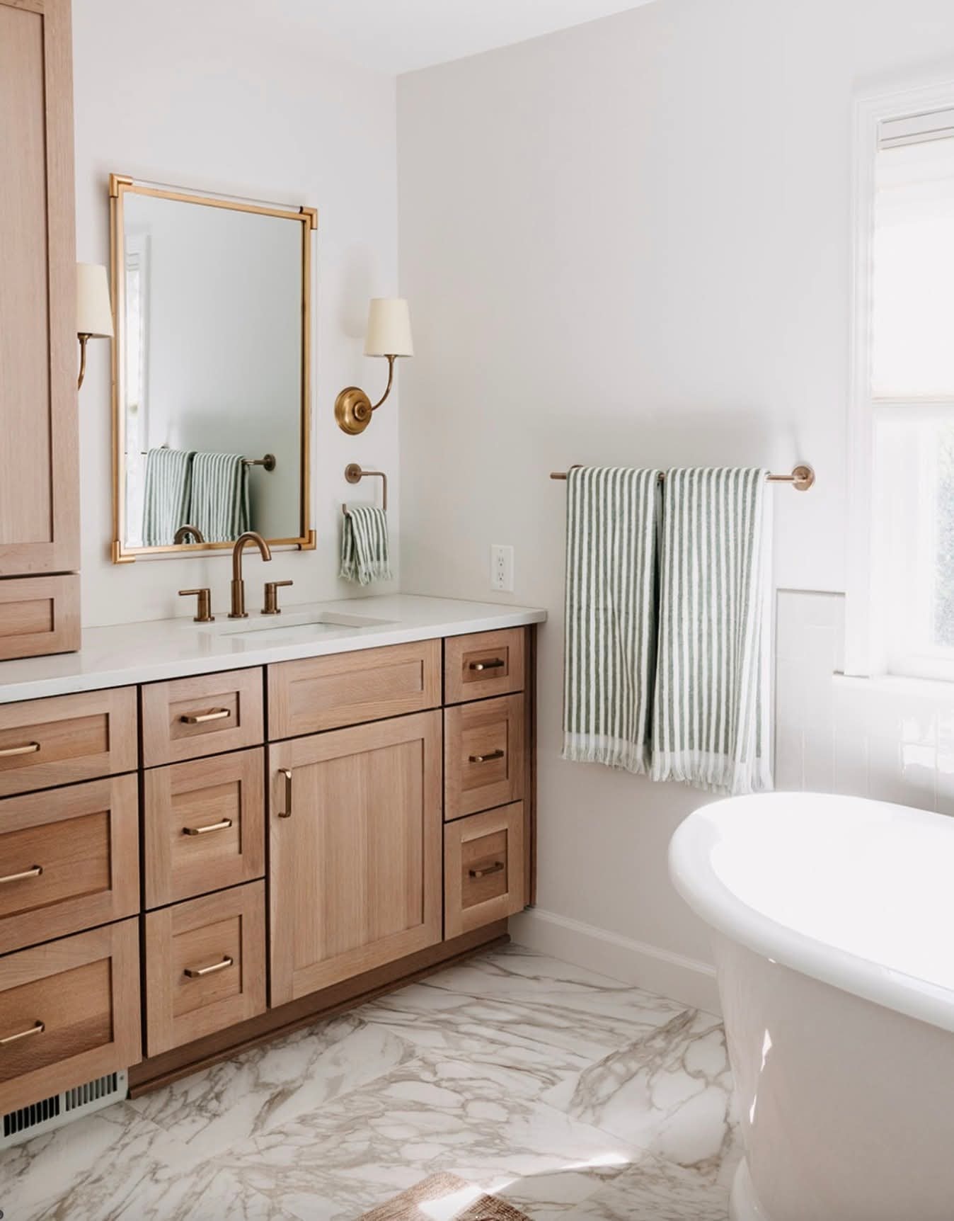 Highlands Ranch primary suite bathroom — freestanding soaking tub and marble-look tile
